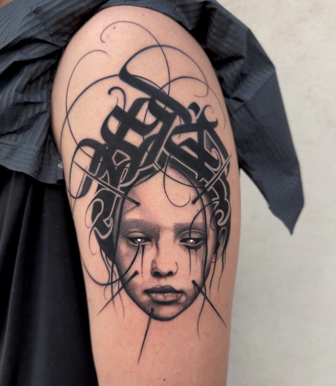 Tatuaggio surreale bambola con lacrime nere e tiara calligrafica gotica Babydrop
